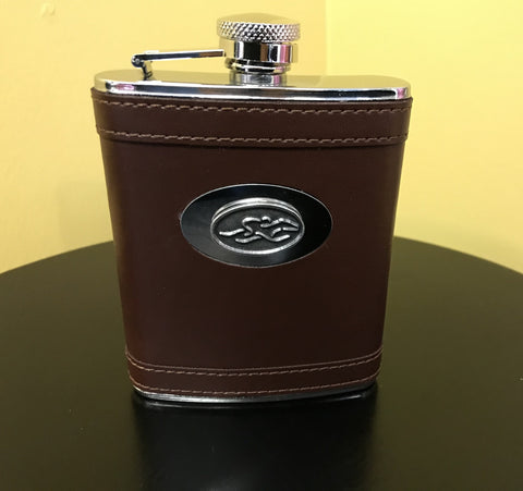 A stain steel flask wrapped in brown leather.  Silver hardware and silver emblemed EMBRACE THE RACE icon center front.