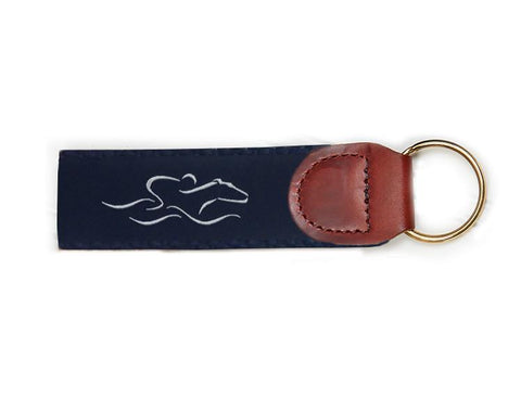 An EMBRACE THE RACE signature key fob with our signature navy and white ribbon on navy backing and brown leather tab.