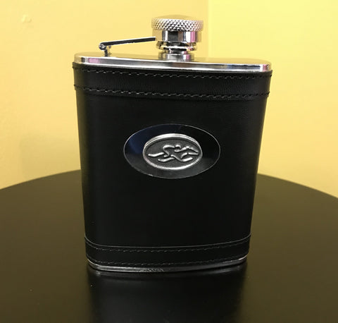 A stain steel flask wrapped in black leather.  Silver hardware and silver emblemed EMBRACE THE RACE icon center front.  